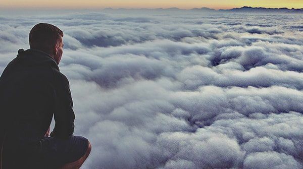 Man on mountain looking out above clouds. Detail Enhancer applied.