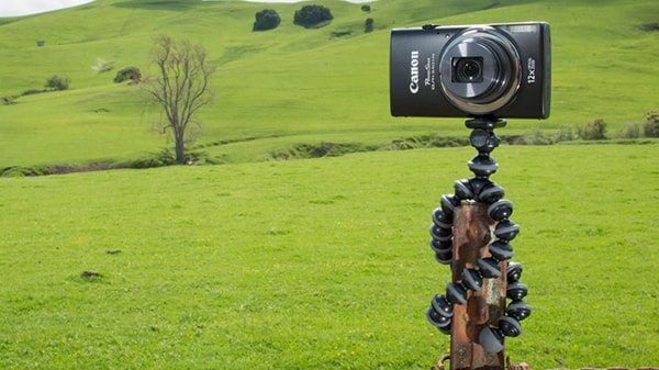 Camera mounted on a flexible tripod in the middle of a field shooting video