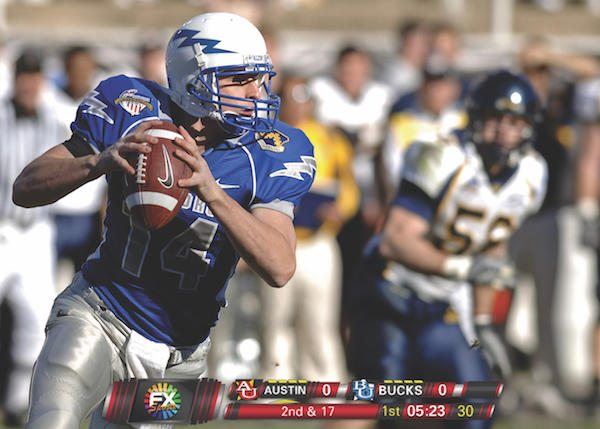 Football player in the middle of a game with a red scoreboard.