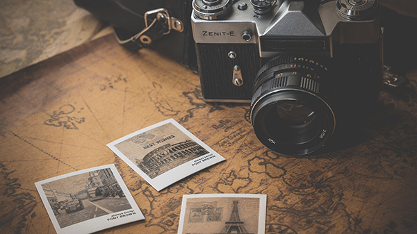 Photo of a vintage camera on a map with polaroids.